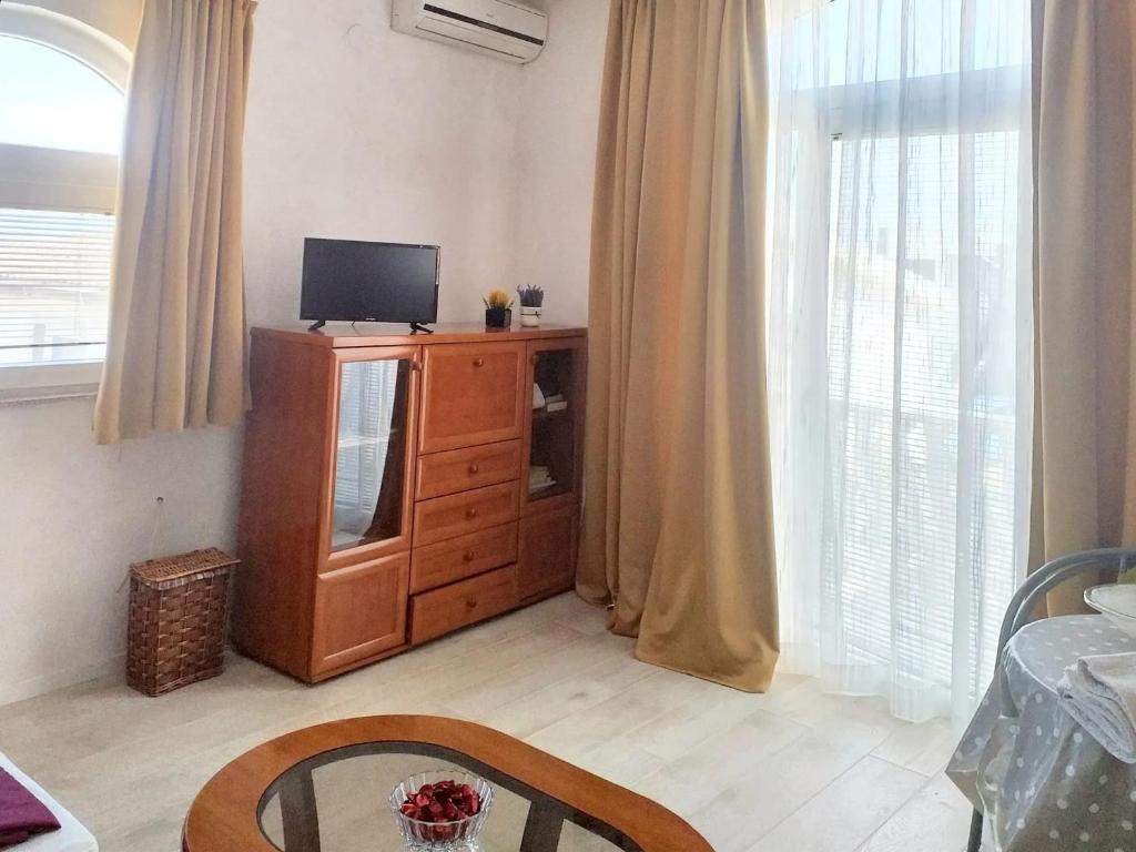 ein Wohnzimmer mit einem TV und einer Holzkommode in der Unterkunft Studio with sea view furnished balcony and wifi at Vir in Vir