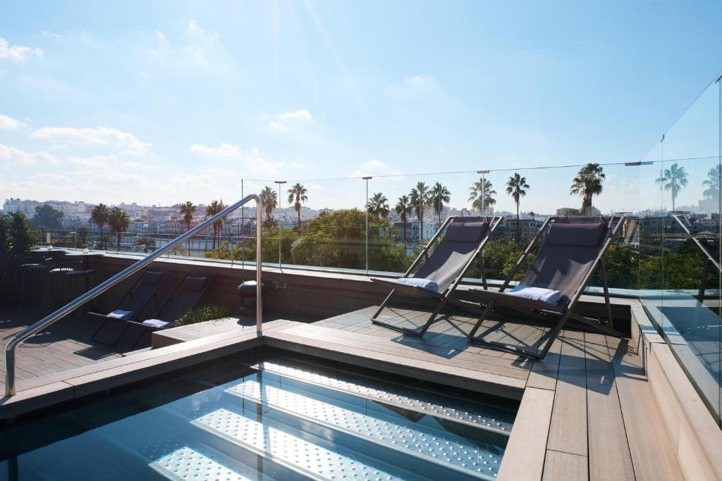 a swimming pool with two chairs on a roof at Hotel Kivir in Seville