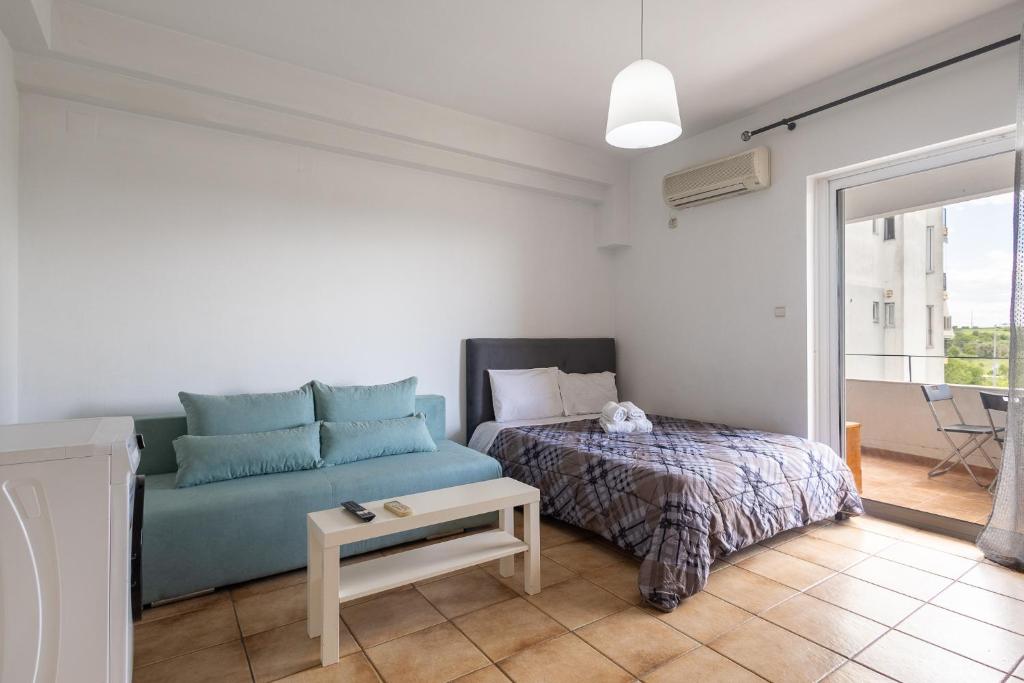 - une chambre avec un canapé bleu et un lit dans l'établissement Elia mini suites 6, à Larissa