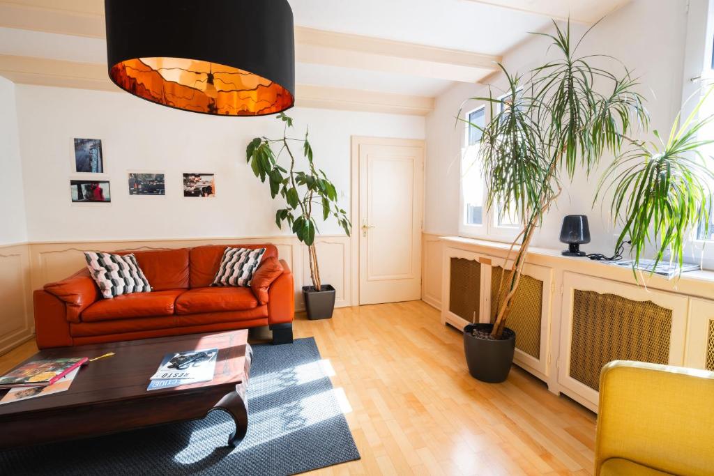 uma sala de estar com um sofá e dois vasos de plantas em La Cour St-Fulrad - Appartements em Saint-Hippolyte