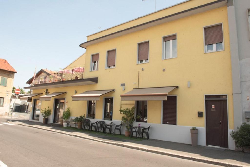 żółty budynek ze stołami i krzesłami na ulicy w obiekcie Il Ragno D`Oro w mieście Rho