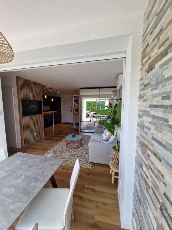 - une salle à manger et un salon avec un mur en pierre dans l'établissement Appartement neuf, à Saint-Laurent-du-Var