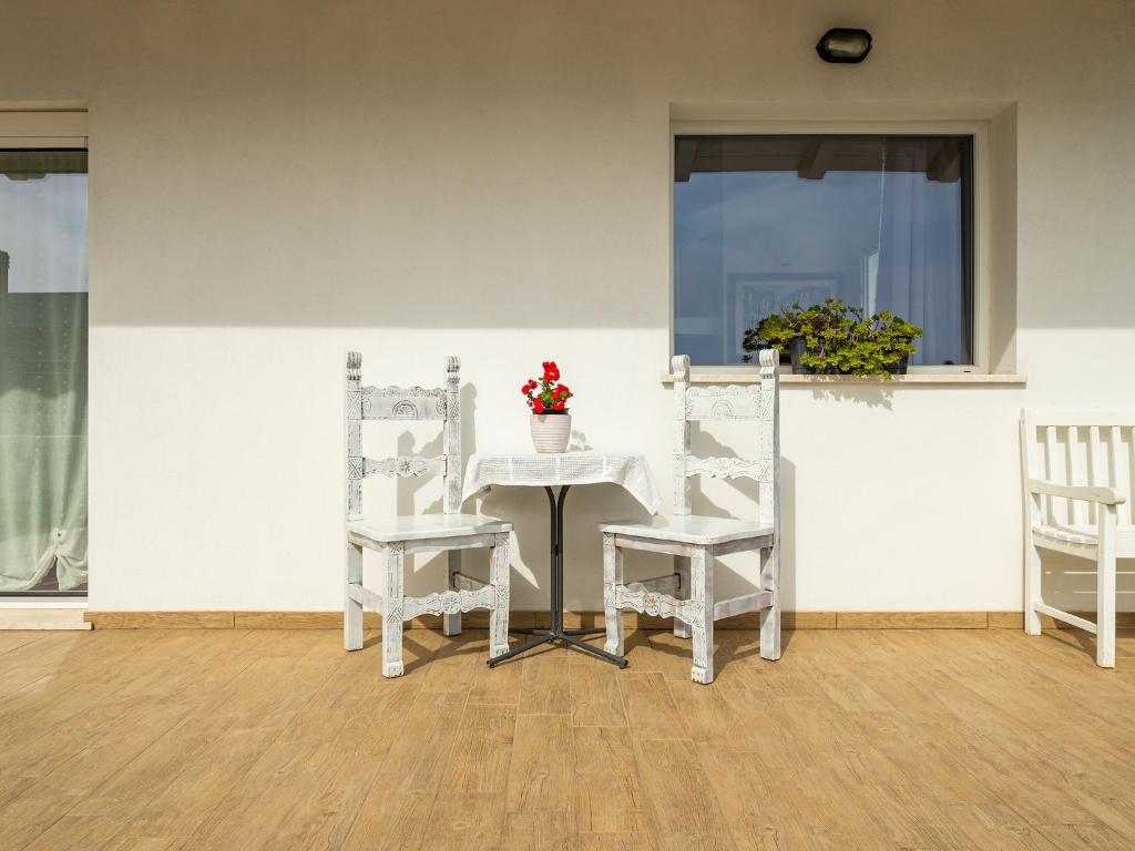 una mesa blanca con dos sillas y una mesa con flores. en Casa Giovele, en Selargius