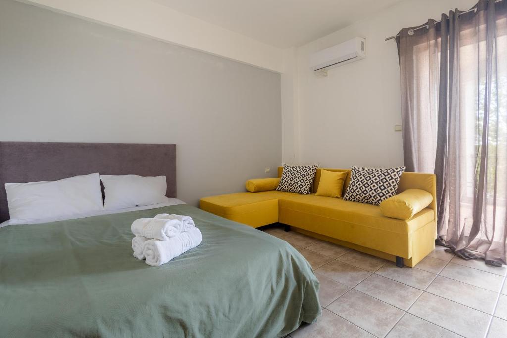 a bedroom with a bed and a yellow couch at Elia mini suites 5 in Larisa