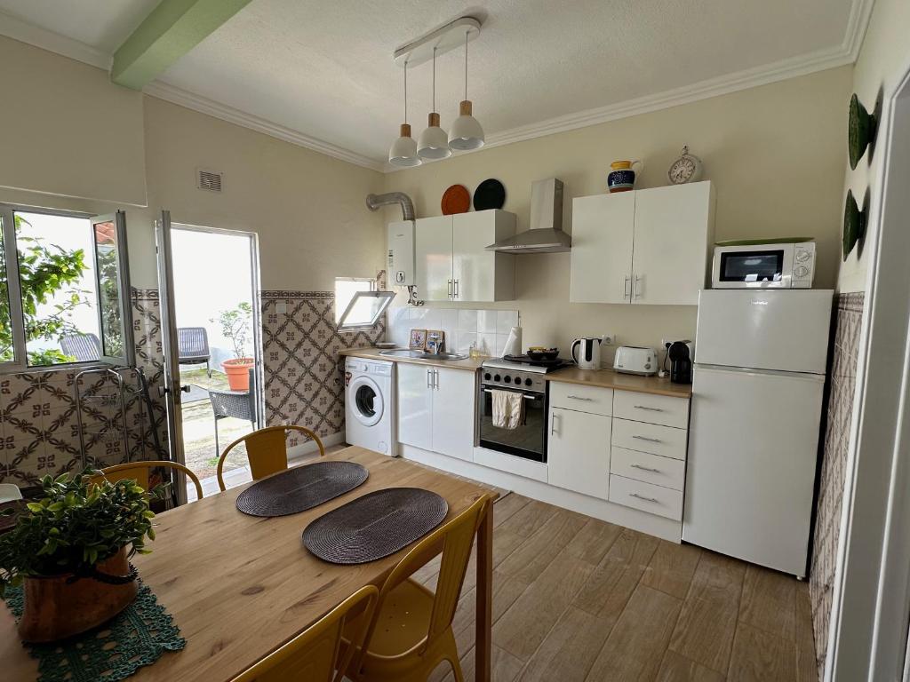 a kitchen with a wooden table and white appliances at Rose's Cottage Foz in Foz do Arelho