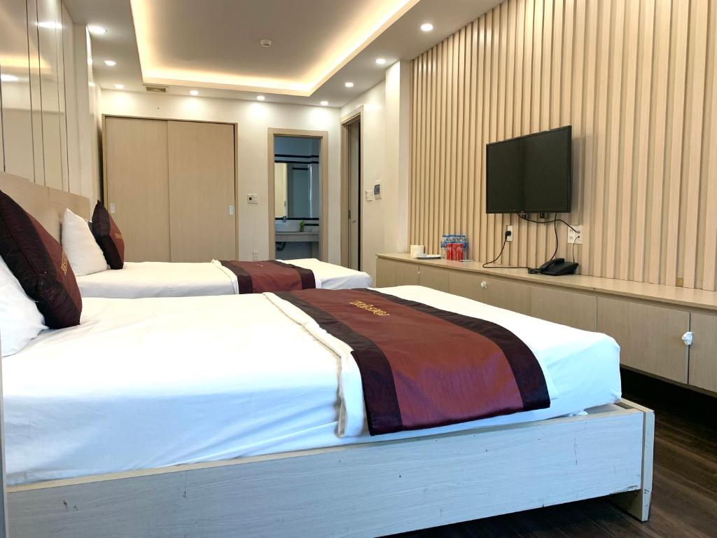 Habitación de hotel con 2 camas y TV de pantalla plana. en Khách Sạn Tom’s en Thái Nguyên