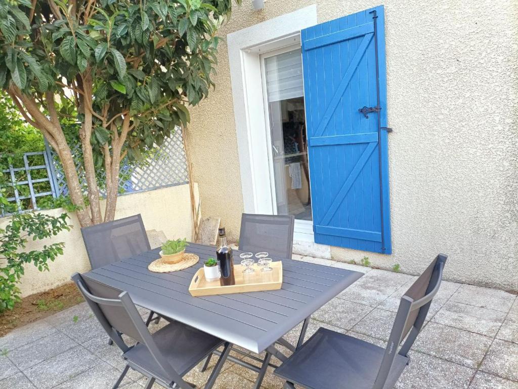 a blue table and chairs with a blue door at Fleur De Sel in Gruissan