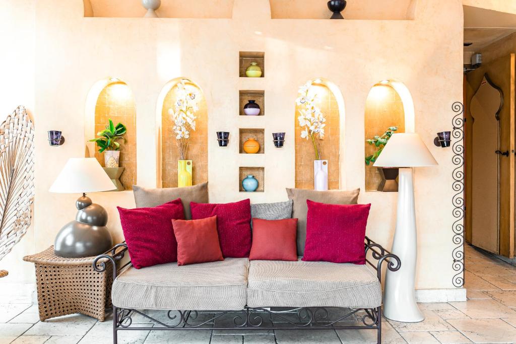 un sofá en una habitación con almohadas rojas en Villa Royale Montsouris, en París