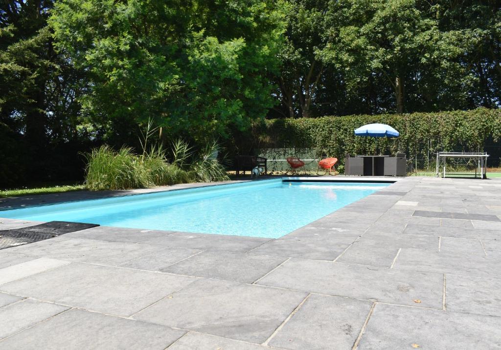 a swimming pool with a table and an umbrella at Rural Studio with Shared Pool, Large Gardens & Tennis, Dog Friendly! Chichester Holiday Properties in Chichester