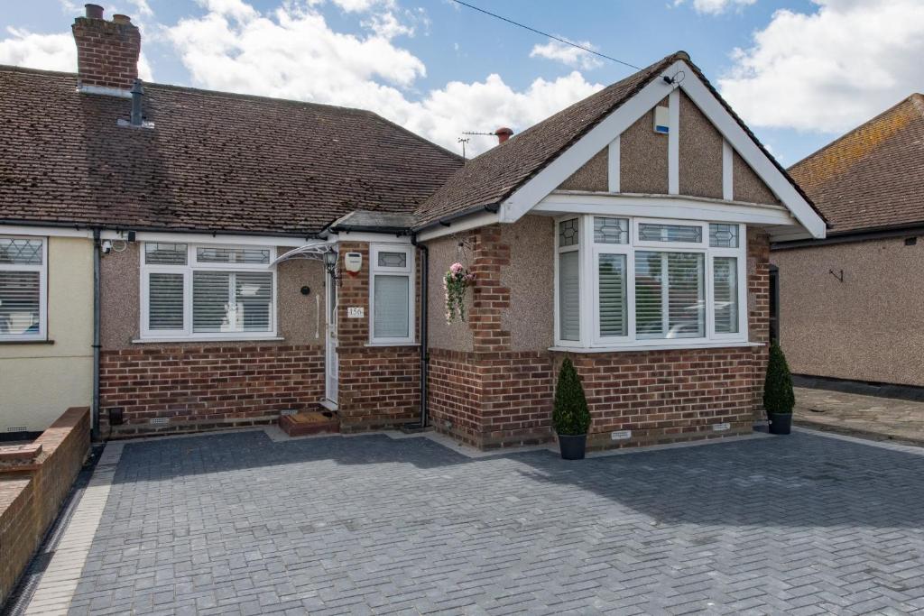 a brick house with white windows and a driveway at Cosy Family Home in Ruislip in Ruislip