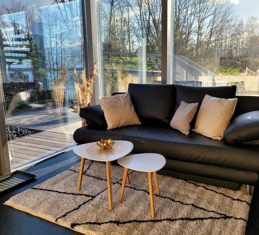 a living room with a black couch and two tables at Appartment Düne 6 1OG Grundbelegung 2 Pers in Elsterheide