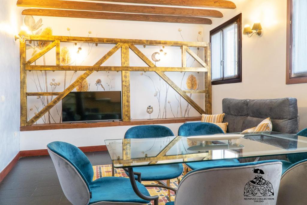 une salle à manger avec une table en verre et des chaises bleues dans l'établissement Casa de la Mezquita y Casa de Carretas MeninasCollection, à Tolède