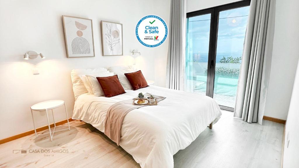 a white bedroom with a large bed and a window at Casa dos Amigos in Santa Cruz