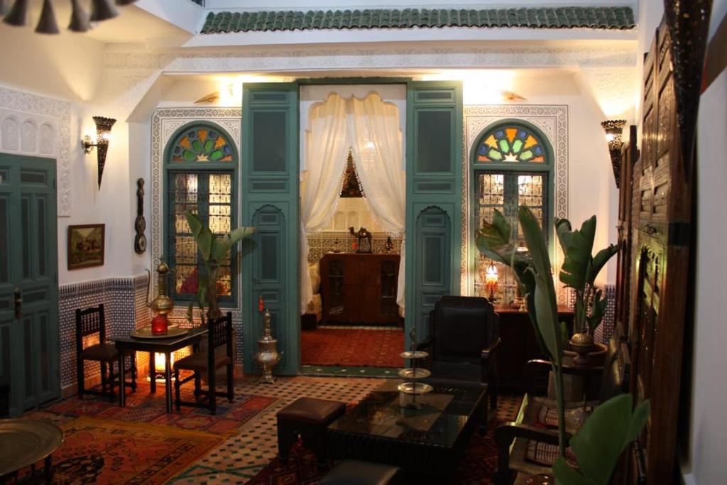 a living room with green doors and a table at Ryad Meknassia in Meknès