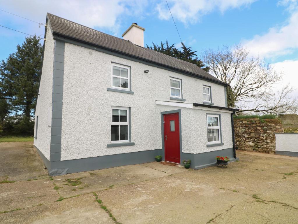 uma casa branca com uma porta vermelha em Curragh Cottage 