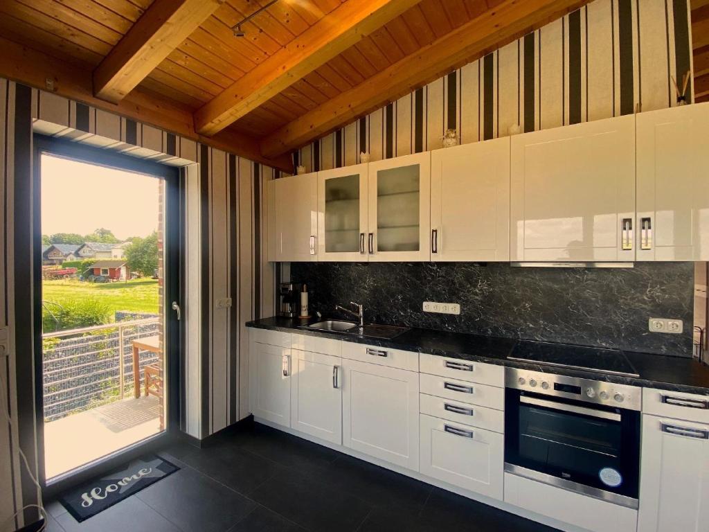uma cozinha com armários brancos e uma grande janela em Wohnung in Schmidt mit Grill und Garten em Nideggen