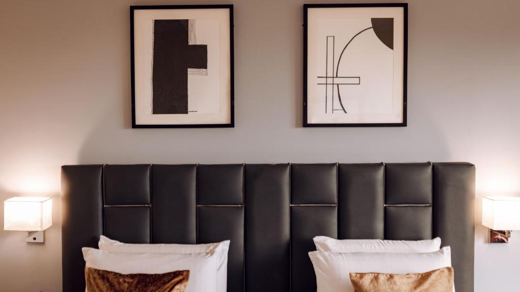 um quarto com uma cabeceira preta e duas fotografias emolduradas em The Metropolitan Hotel Calabar em Calabar