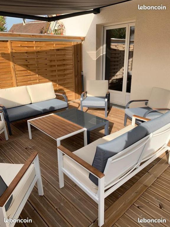 une terrasse avec des canapés, une table et des chaises dans l'établissement L' Atelier sur les plages du débarquement, à Asnelles