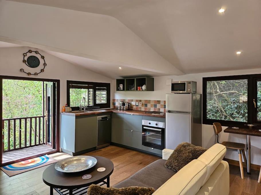 a kitchen and living room with a couch and a table at Treetops Lodge, private parking & garden in Truro