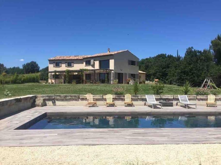 une maison avec une piscine, des chaises et une maison dans l'établissement Villa avec piscine, au calme et en pleine nature!, à Pierrevert