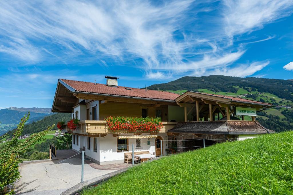 una casa al lado de una colina con flores en Ferienwohnung Ausblick Zillertal, en Hainzenberg