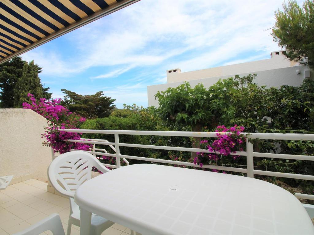 une table et des chaises blanches sur un balcon avec des fleurs violettes dans l'établissement Apartamento Llançà, 2 dormitorios, 6 personas - ES-228-155, à Llançà