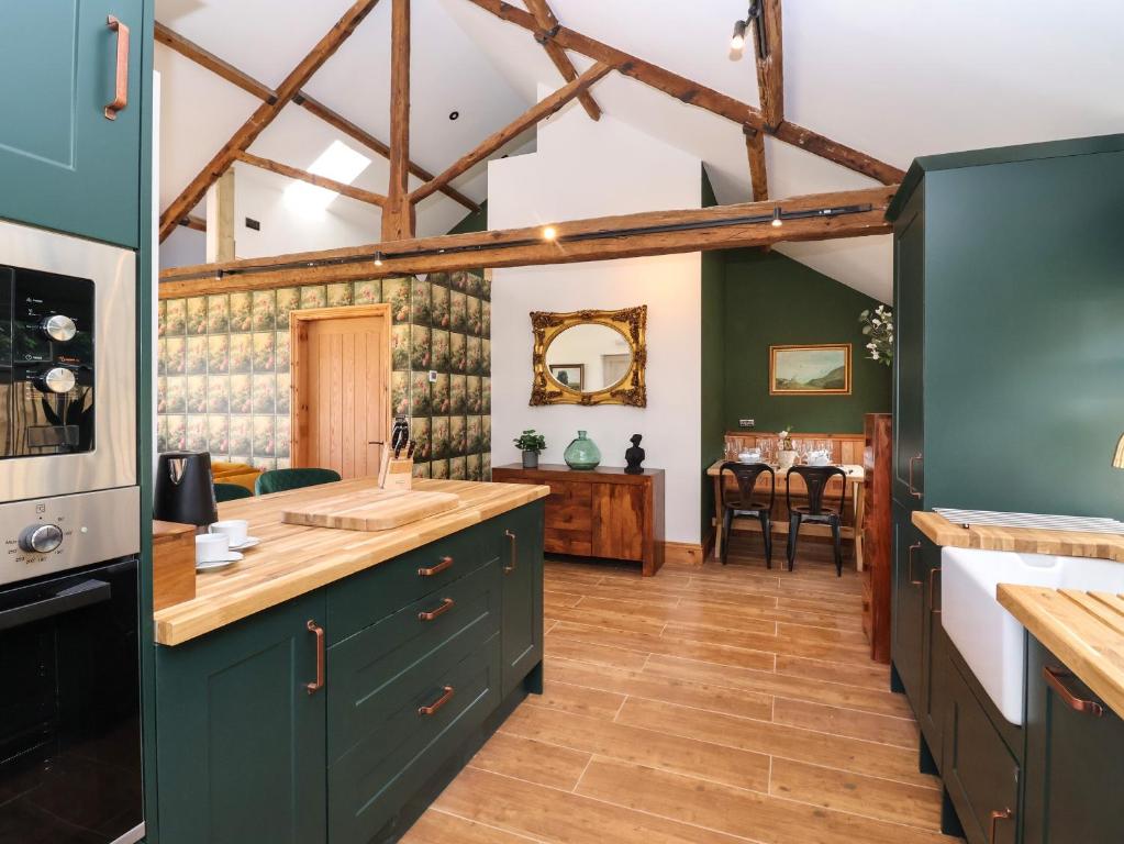 Nell's Cottage في مالتون: مطبخ مع دواليب خضراء وارضيات خشبية