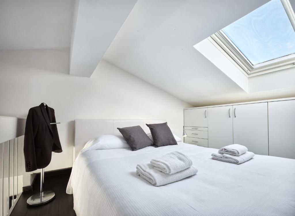 - une chambre blanche avec un lit et des serviettes dans l'établissement STUDIO THE BEACH - Regarda Travel, à Bardolino