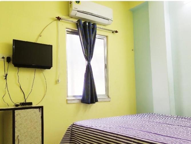 a bedroom with a bed and a window with a curtain at Amar Priya guest house in Kolkata