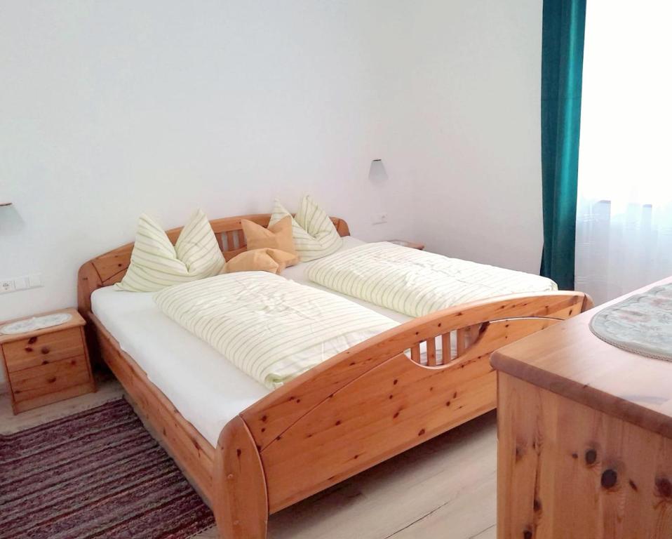 a wooden bed with white sheets on it in a room at Ferienwohnung Steuerberg in Feldkirchen in Kärnten