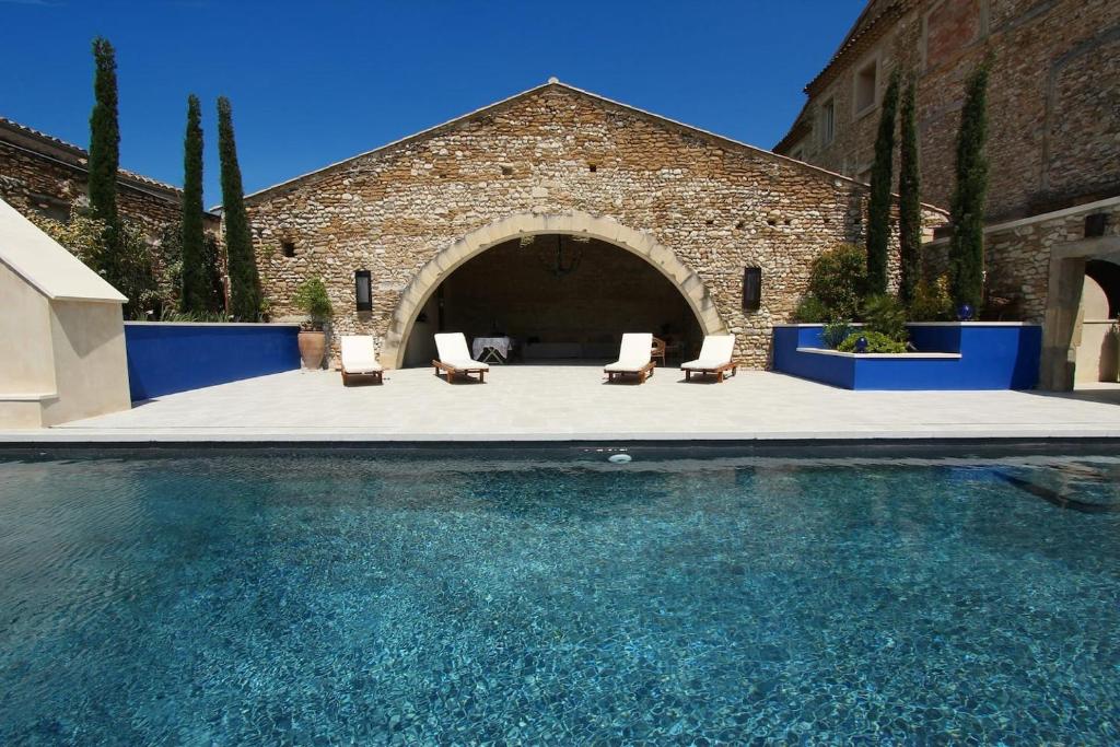 ein Pool mit Stühlen und ein Backsteingebäude in der Unterkunft Luxury Retreat in Valréas in Valréas