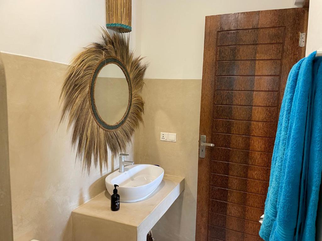 a bathroom with a sink and a mirror on the wall at Sand Beach Boutique Hotel in Bwejuu