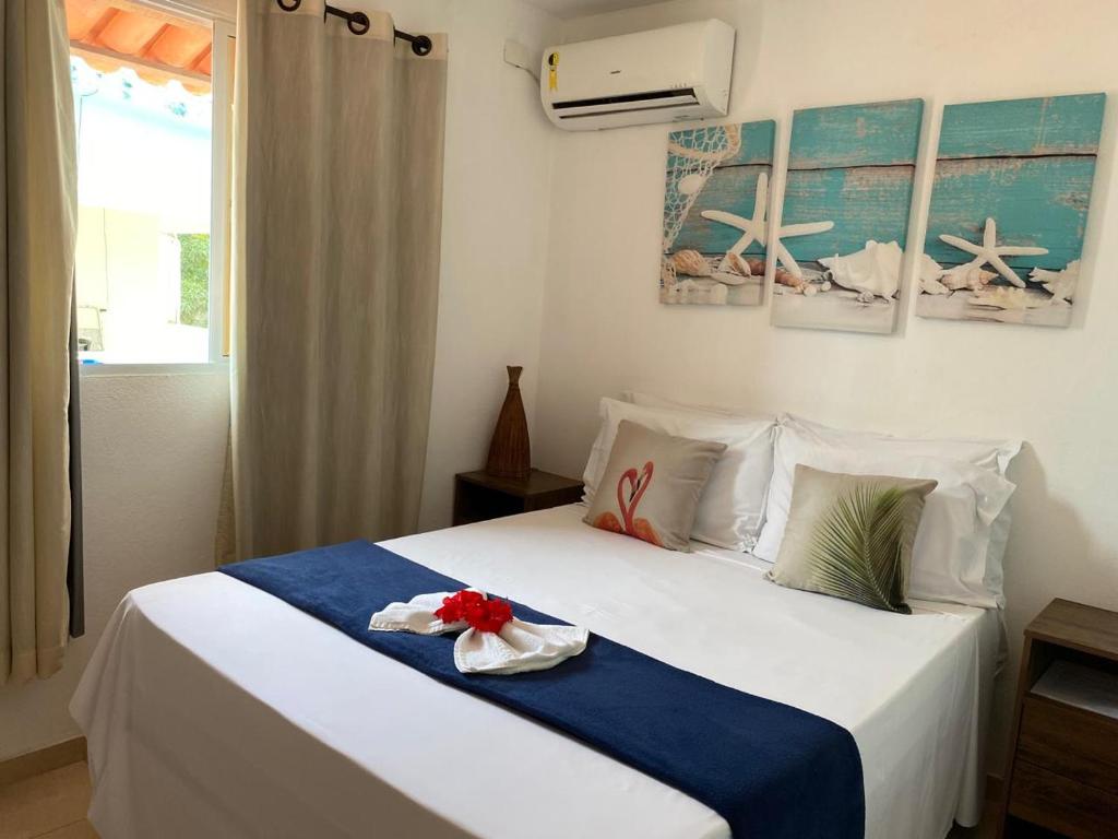 um quarto com uma cama branca e um cobertor azul em Kailua apartamentos e suítes em Porto de Galinhas