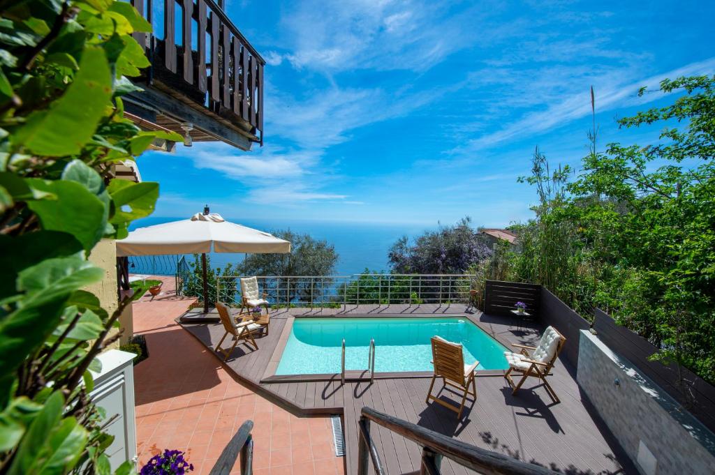 un patio con piscina, sillas y sombrilla en Solaria, en Amalfi