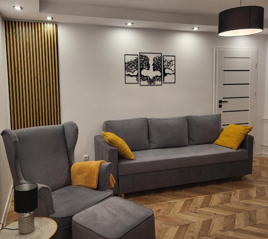 una sala de estar con un sofá y dos sillas en Apartament M&K z widokiem na Stare Miasto, en Zamość