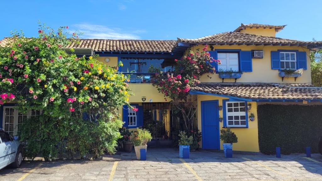 una casa amarilla con puertas azules y flores en Pousada Repouso do Guerreiro, en Búzios