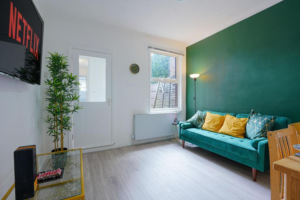 ein Wohnzimmer mit einem blauen Sofa und einem Fenster in der Unterkunft Modern Freshly Refurbed Home Luton in Luton