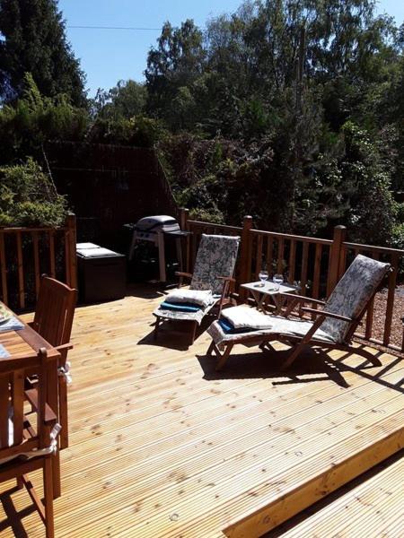 two chairs and a table on a wooden deck at Deerdale Lodge in Bilsthorpe