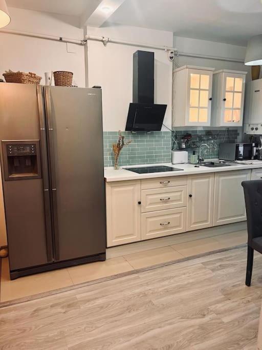 a kitchen with a stainless steel refrigerator and white cabinets at Lorand's Place near the River in Cluj-Napoca