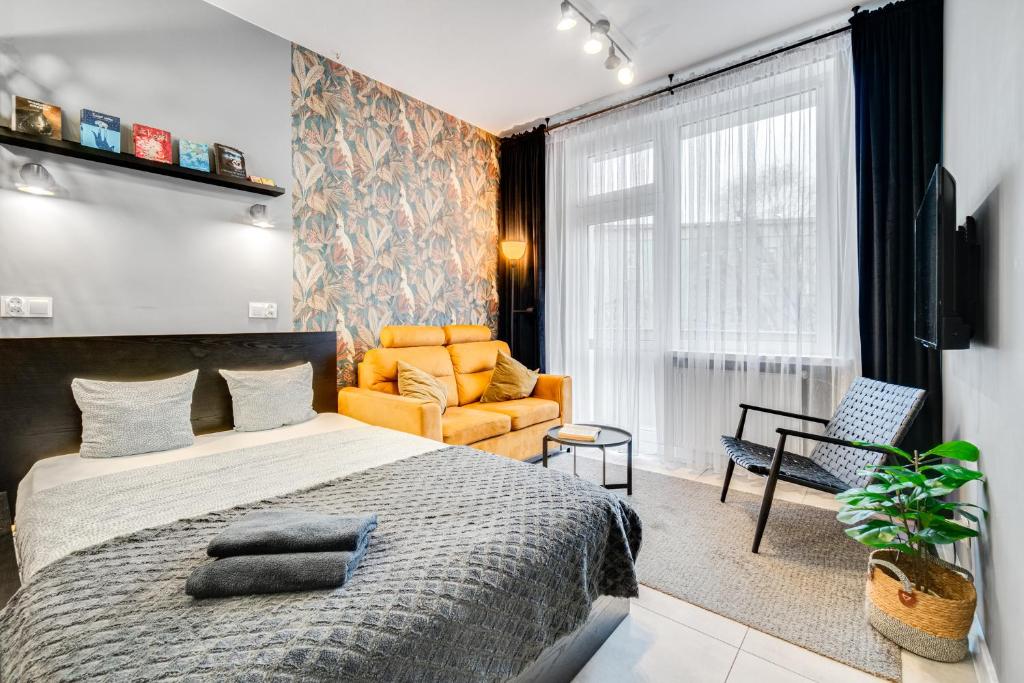 ein Schlafzimmer mit einem Bett, einem Stuhl und einem Sofa in der Unterkunft PAPUGA Apartment ~ 700m Main Square ~ Self check-in 24h in Breslau