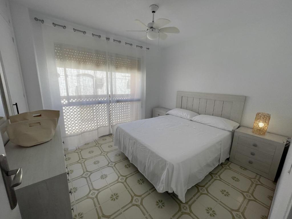 een witte slaapkamer met een bed en een raam bij Calabardina Playa 2 con Wifi in Calabardina