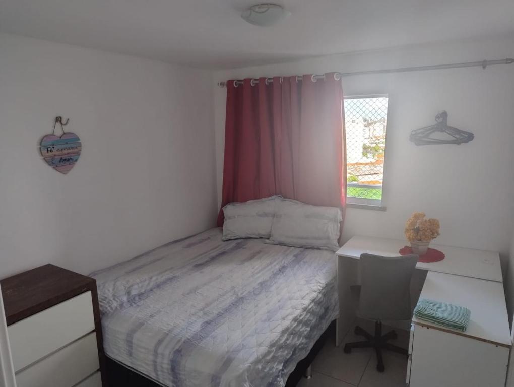 a bedroom with a bed and a desk and a window at Quartos - Cíntia in Fortaleza