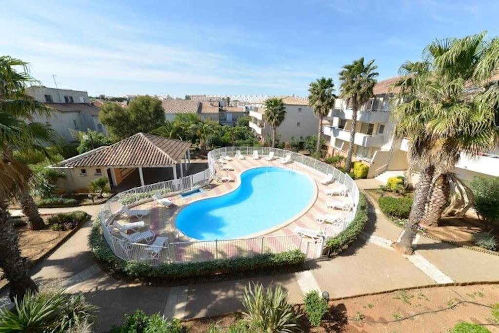 una imagen de una piscina en un complejo en Appartement 2CH, clim, piscine, garage, mer, en Le Grau-du-Roi