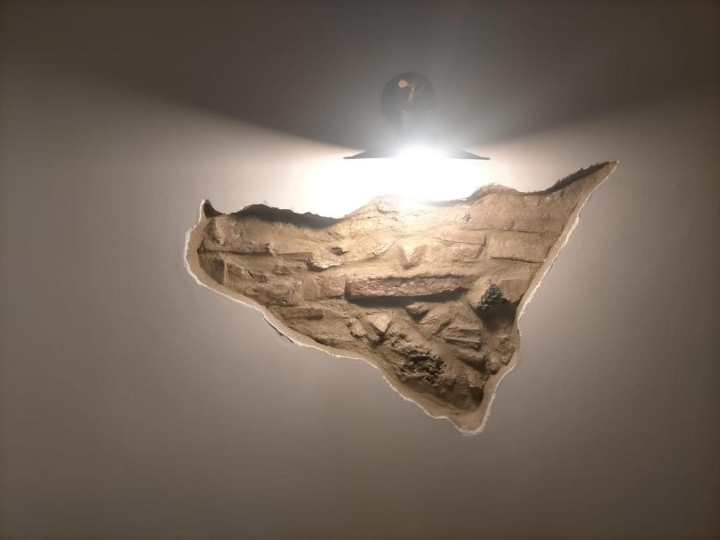 uma luz pendurada numa parede com uma obra de arte em Petite Etoile em SantʼAgata di Militello