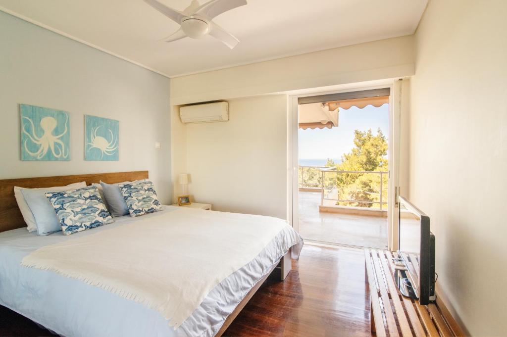 Schlafzimmer mit einem Bett und einer Glasschiebetür in der Unterkunft Vouliagmeni Sea and Sun Apartment in Athen