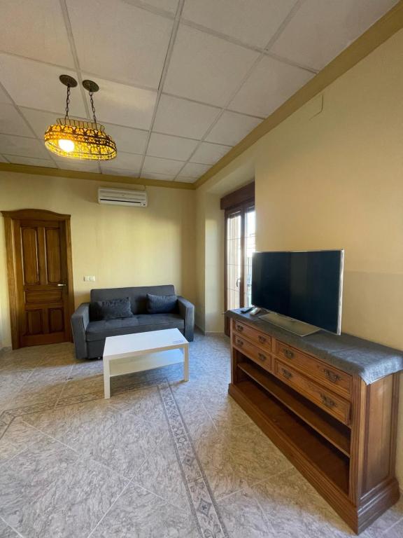 a living room with a couch and a flat screen tv at Apartamentos Abeto in Ronda