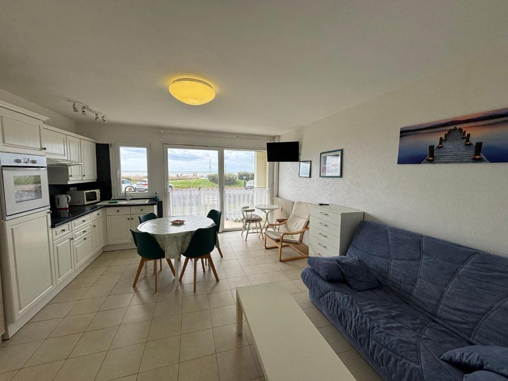 een woonkamer met een bank en een tafel met stoelen bij Studio en résidence face mer avec parking in Le Touquet-Paris-Plage