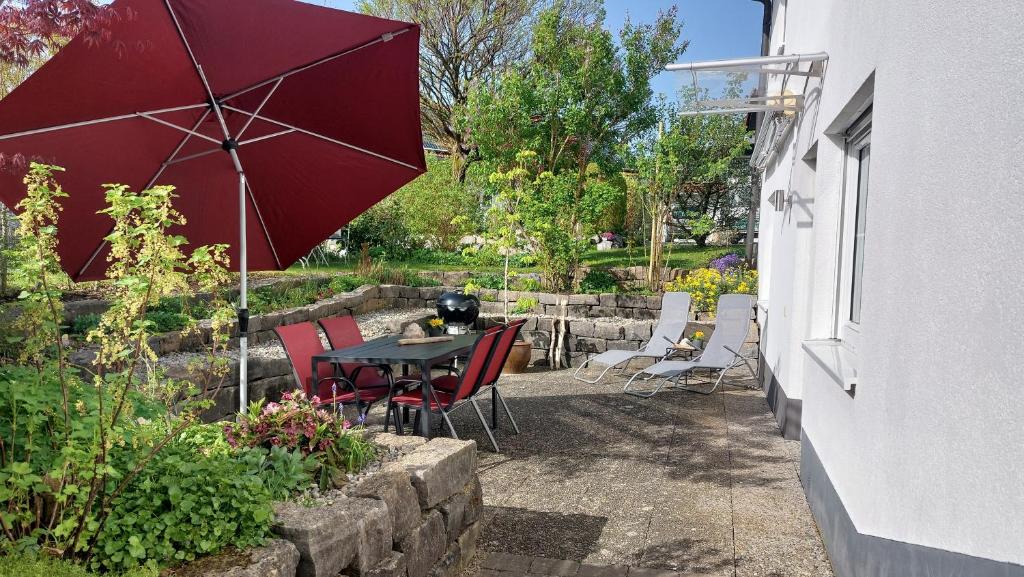 patio con tavolo, sedie e ombrellone di Ferienwohnung Mutz a Sigmarszell