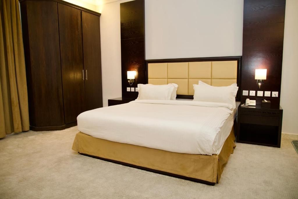 um quarto com uma cama grande com lençóis brancos e almofadas em فندق أصداء الراحة Asdaa Alraha Hotel em Jidá