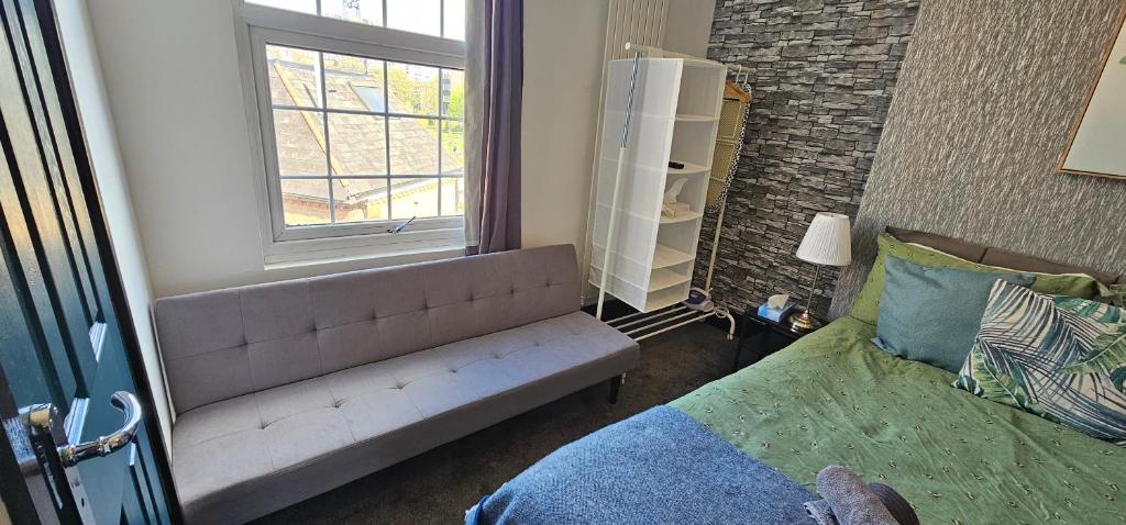 a bedroom with a couch next to a window at 10 Minutes to Central London Vaux in London